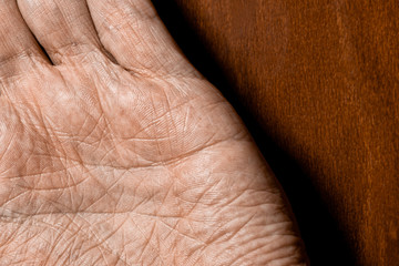 Picture of elderly male hands on a wooden background. Detail of the palm of the hand.