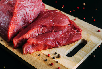 Fresh and raw meat. Whole piece of red beef ready to cook on the grill or BBQ . Background black blackboard.