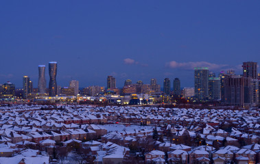 Ariel view of snow covered rooftops of north american neighborhood houses in Mississauga, Ontario, Canada. Light trails of head and tail lights cars going on the highway in the evening
