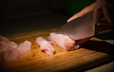 Chef cutting raw chicken filet close up.