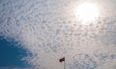 Fototapeta na wymiar Cirrocumulus clouds in the blue sky. Turkish flag on the background of clouds and ahead.