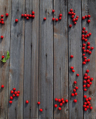 Red sweet hawthorn berries scattered on a smoky wooden background for Christmas greetings or for Valentine's Day.