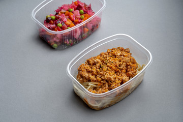 Pasta with minced meat and onion in navy-style and a jar of vinaigrette on a gray background.