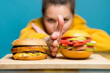 woman separates meat burger and vegetarian burger with her palm