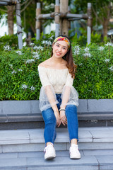 Portrait of beautiful sexy Asian woman sitting on step in the garden