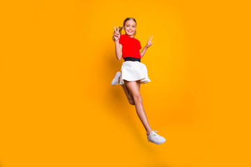 Full length profile photo of pretty funny little lady pretty long tails jumping high showing v-sign symbols wear casual red white dress sneakers isolated yellow color background