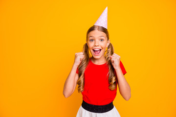 Photo of pretty small lady long tails hairstyle celebrating birthday party good mood raise fists wish open gifts wear paper hat casual red white dress isolated yellow color background