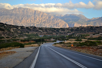 Asphalt road meanders and leads to beautiful sunset mountains