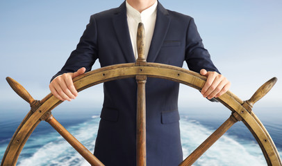 Businessman holding ship rudder with blue sea on background. Leader Concept. © Anton Sokolov