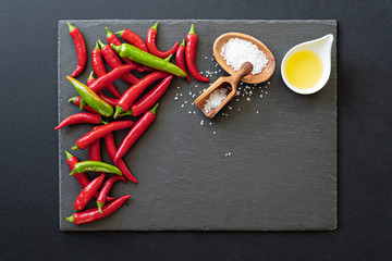 Chilli rot und grün mit Salz und Öl auf Schieferplatte