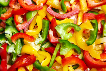 Colorful pieces of sweet peppers, texture, background. Chopped red, green, yellow bell peppers, top view. Vegetable salad ingredient, cooking healthy diet food