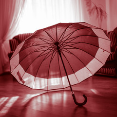 open umbrella standing on the laminate floor in the sunny room.