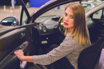 Young woman getting out of the parked car opening door looking to the camera mad angry furious pissed on the parking in the city at night