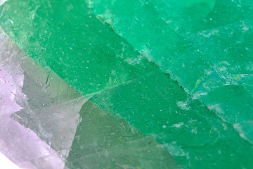 Close up detail on the surface of a green magenta and translucid fluorite mineral stone crystal isolated on white limbo background