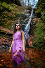 Portrait of a beautiful hispanic young woman near waterfall in autumn season