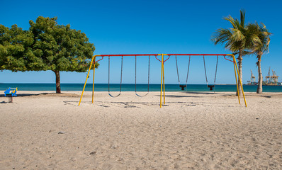 a lonley colorful  swing on the beach witha blue sky 