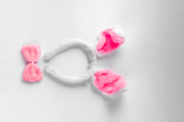 Top view of cute bunny ears with a small pink bow on wooden background.