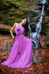 Obraz na płótnie Canvas Portrait of a beautiful hispanic young woman near waterfall in autumn season