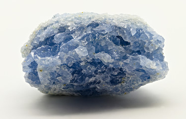 Close up on natural rough celestite or celestine mineral stone with blue crystals against white limbo background