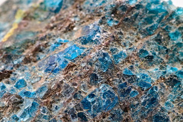 Lazulite crystals on a black rough mineral specimen, against a white limbo background