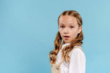 shocked and cute kid looking at camera isolated on blue