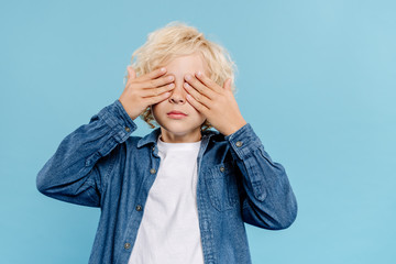 kid in denim shirt obscuring face isolated on blue