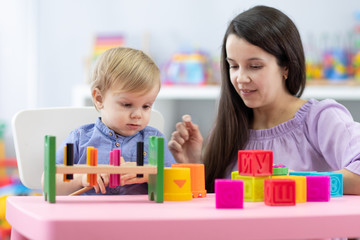Fototapeta premium Mother and child toddler playing with educational toys together at home