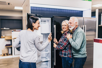 Obraz premium Senior husband and wife, satisfied customers choosing fridges in appliances store.