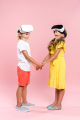 shocked kids with virtual reality headset holding hands on pink background