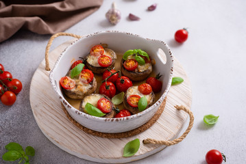 Baked mushroom caps stuffed with fried mushrooms, onion, cheese, tomatoes and spices. Side view. Vegeterian dish