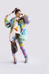 Woman wearing plastic on white background. Female model in clothes and shoes made of garbage....