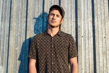 Portrait of a modern guy in a casual dress with a cap on the street. Photography style social networks. Young lifestyle concept