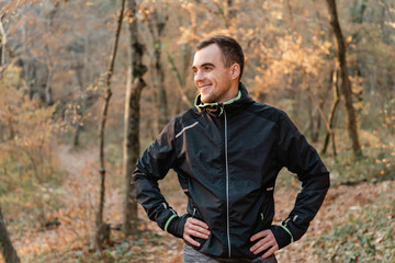 Concept of sport and active lifestyle. A young man in a black tracksuit, posing with a smile in the autumn Park
