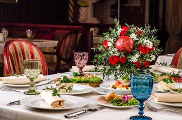 Served for holiday banquet restaurant table with dishes, snack, salads, cutlery, wine and water glasses. European food in a restaurant setting. Table set for an event party. catering