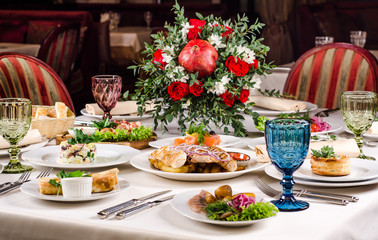 Served for holiday banquet restaurant table with dishes, snack, salads, cutlery, wine and water glasses. European food in a restaurant setting. Table set for an event party. catering