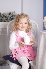 girl sits at a table and drinks from a large porcelain cup