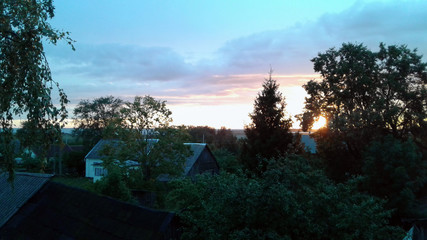 Sunset in the village. The departing rays of the sun make their way through a tree. Far from the...