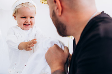 Father is playing with a little daughter. Child in a white dress with dad.