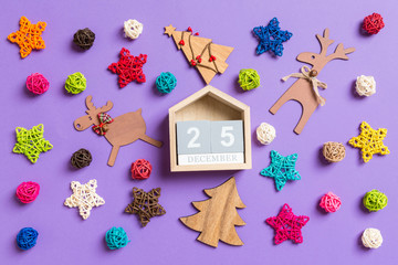 Top view of wooden calendar. The twenty fifth of December. New Year decorations on purple background. Festive stars and balls. Merry Christmas concept