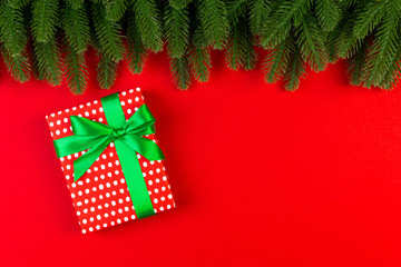 Top view of gift box and fir tree branches on colorful background. Merry Christmas concept with empty space for your design