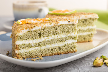 Homemade cake with milk cream and pistachio with cup of coffee on a gray concrete background. side view, selective focus.