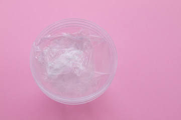 plastic dish and plastic cup on  pink paper background