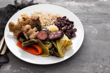 typical portuguese dish boiled meat, smoked sausages, vegetables and rice on white plate