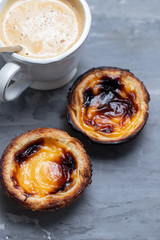 typical portuguese egg tart pastel de nata with cup of coffee on ceramic background