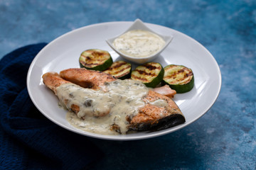 salmon with sauce and grilled vegetables on white plate
