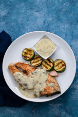 salmon with sauce and grilled vegetables on white plate