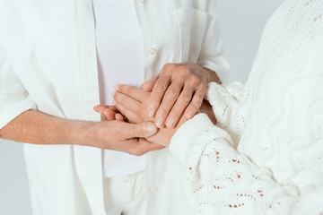 cropped view of mother and daughter holding hands isolated on grey