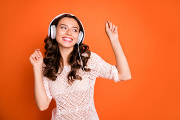 Portrait of charming cute girl listen music on her modern headset like playlist dance wear good looking outfit isolated over orange color background