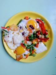 eggs benedict with vegetables on a yellow plate