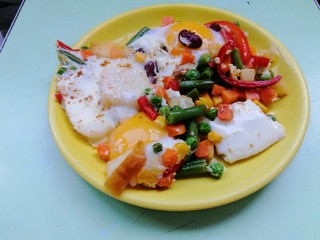 eggs benedict with vegetables on a yellow plate